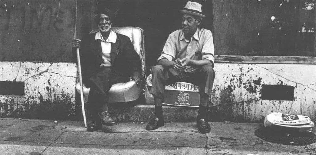 Two men in slacks sitting on a stoop, in black and white