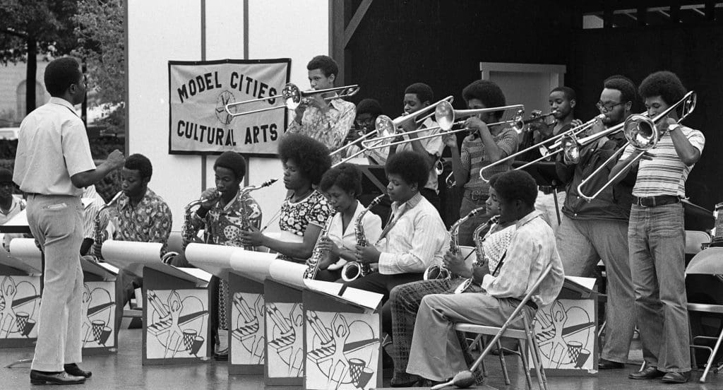 band on stage with model cities cultural arts sign