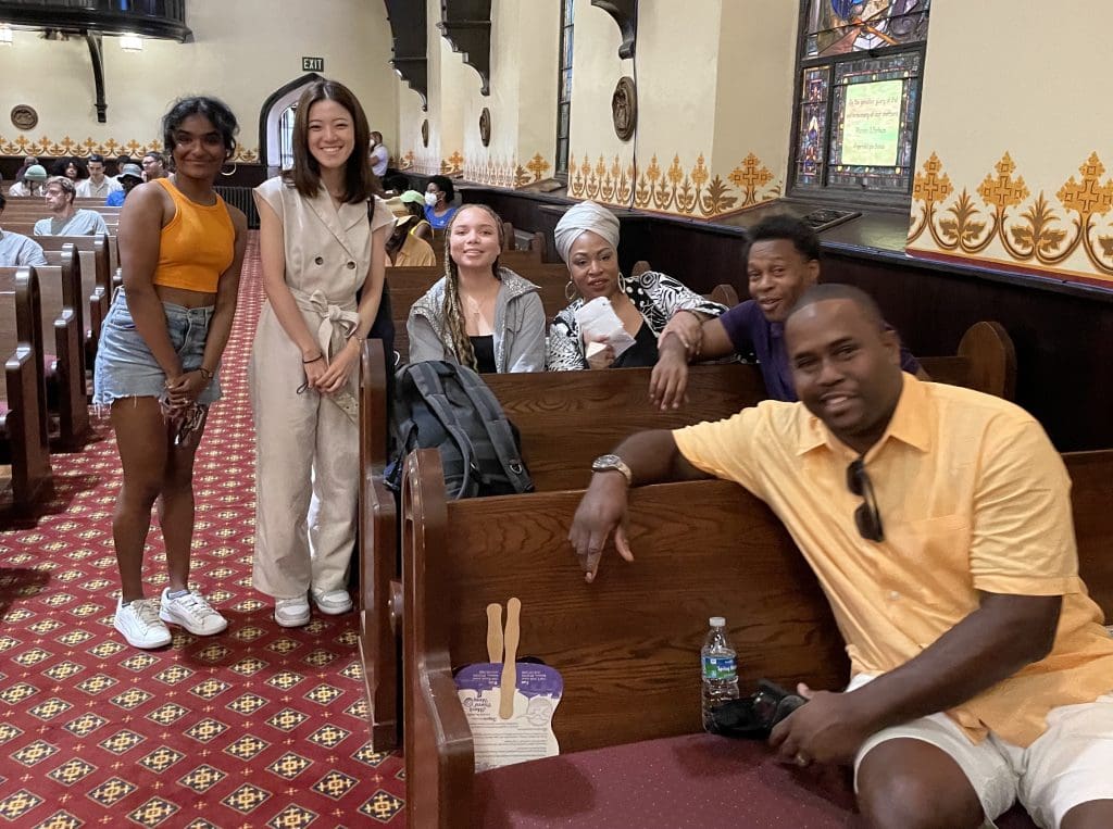 six people smiling together in and alongside church pews