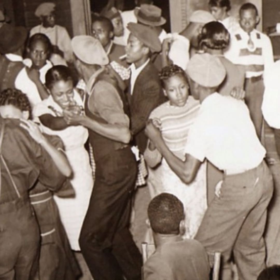 A black-and-white photo of Black men and women dancing in a crowded room