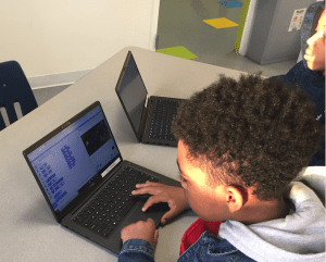 an elementary school kid working on a laptop