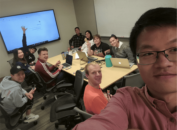 a person taking a group selfie at a conference table
