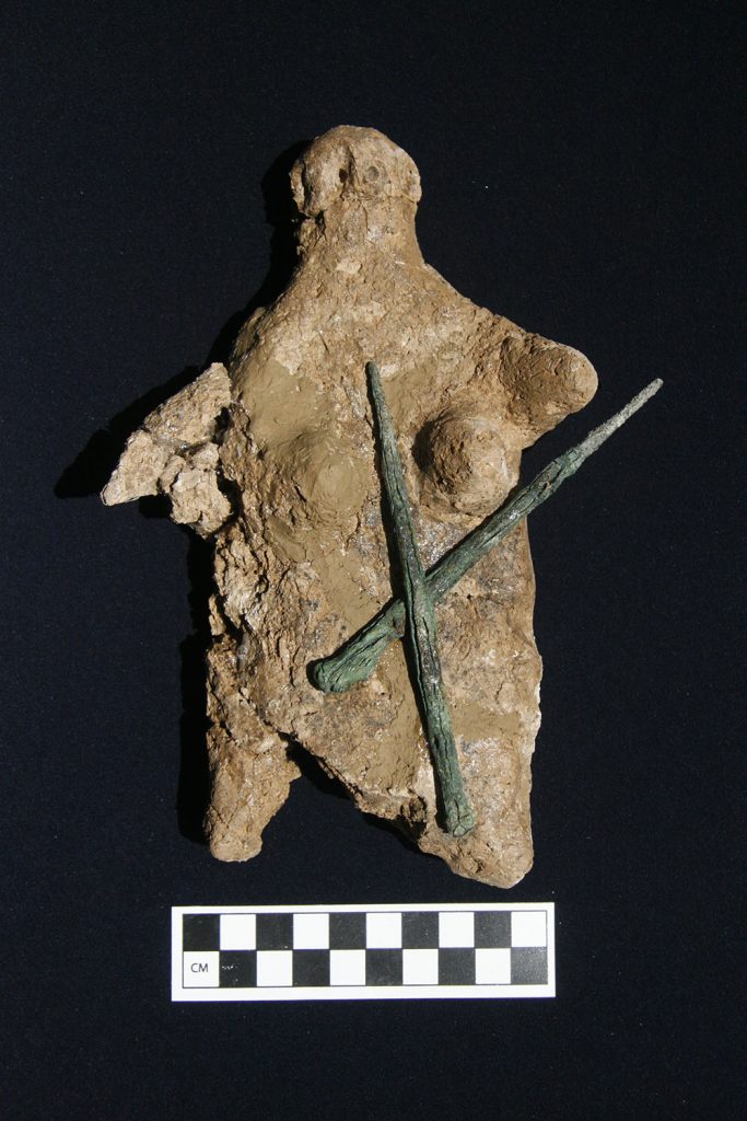 Clay female statuette with bronze toggle pins.