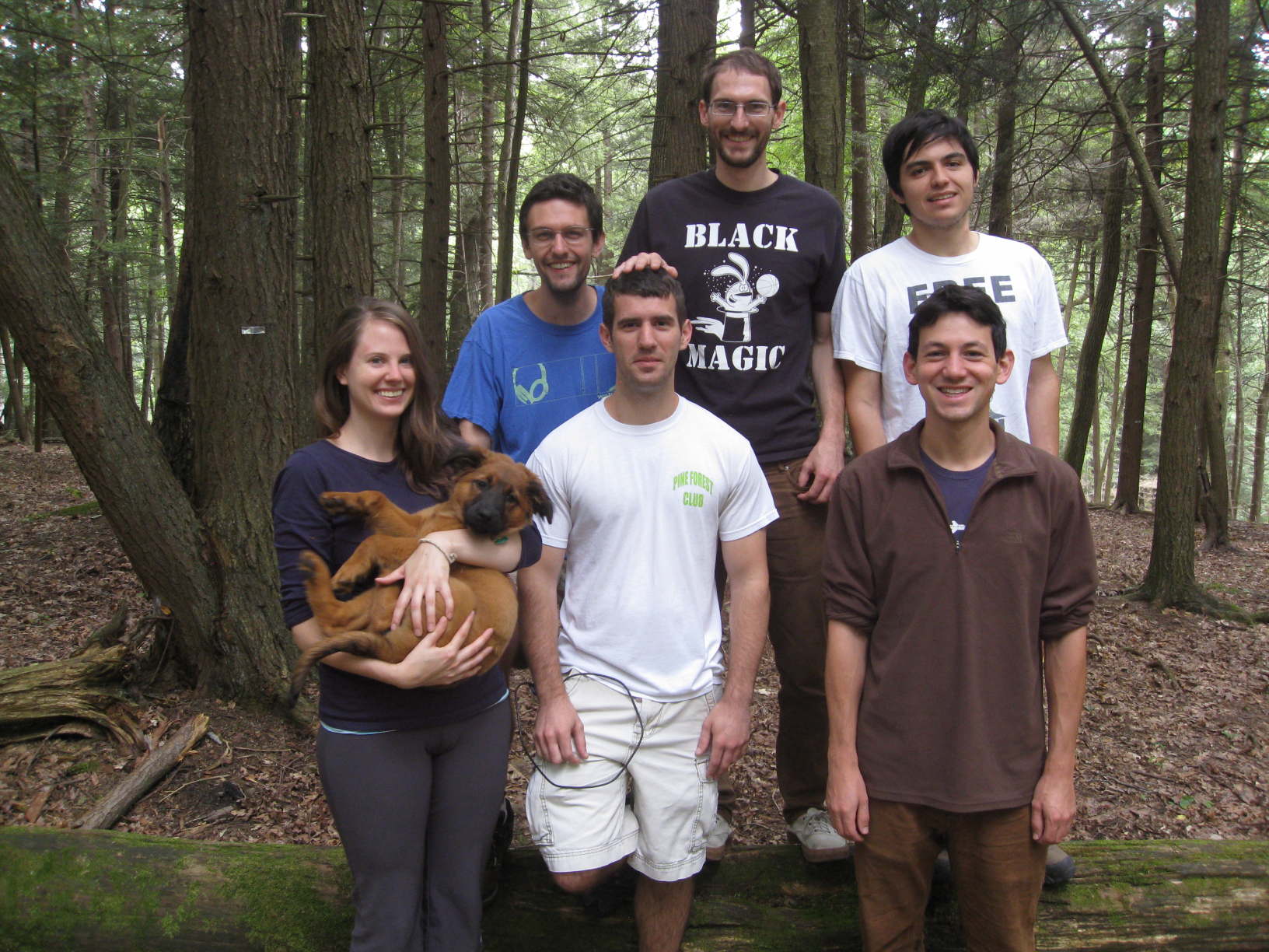 Six people and a dog smiling in the woods
