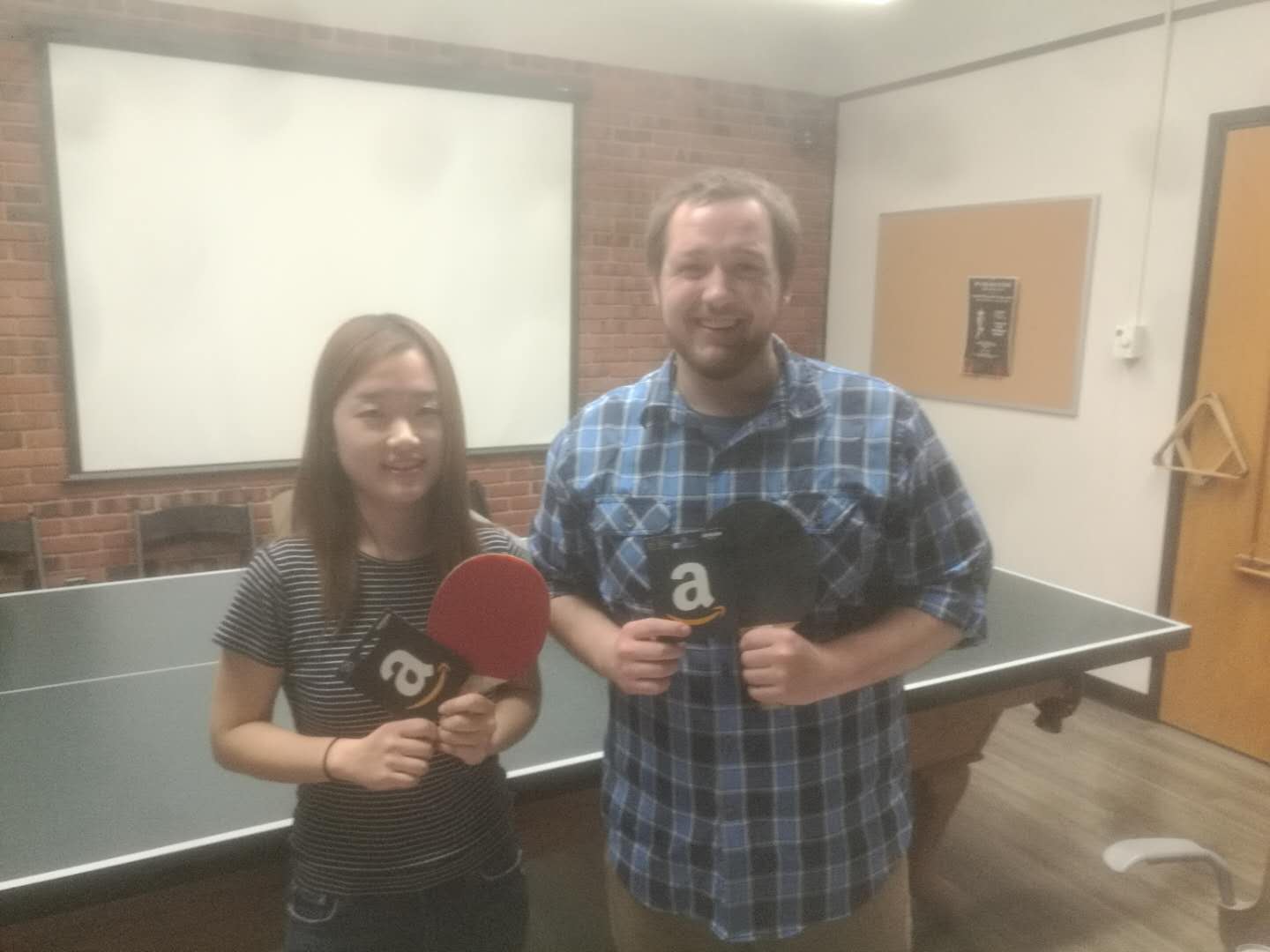 A woman and a man with ping pong paddles and Amazon gift cards