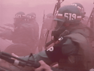 Blurry image of military policeman enveloped in a pink cloud of smoke