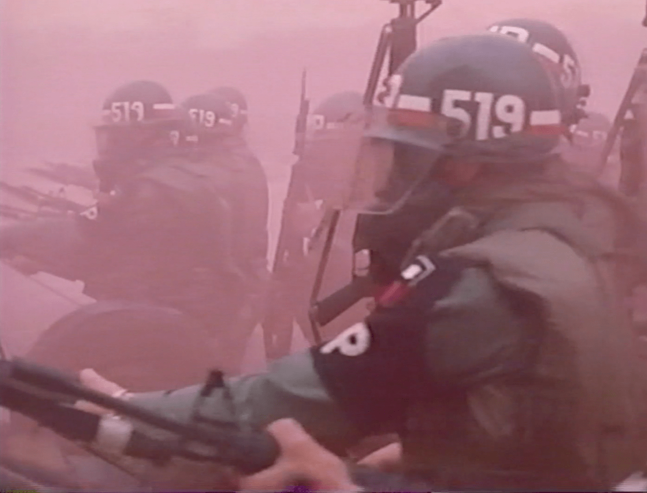 Blurry image of military policeman enveloped in a pink cloud of smoke
