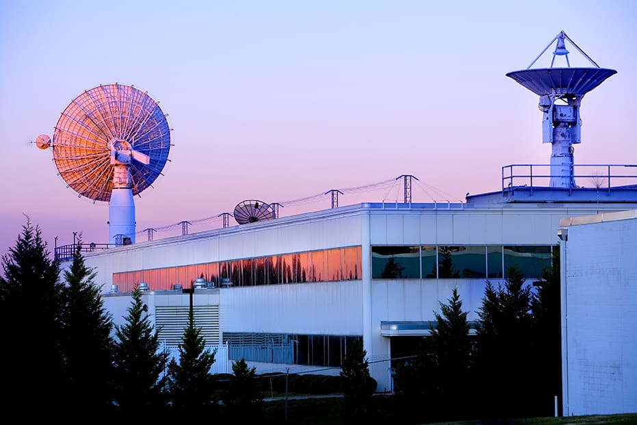 Modernist building with satellite dishes at sunset