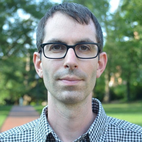 headshot of Stuart Schrader, white man with glasses and short dark hair in checked shirt